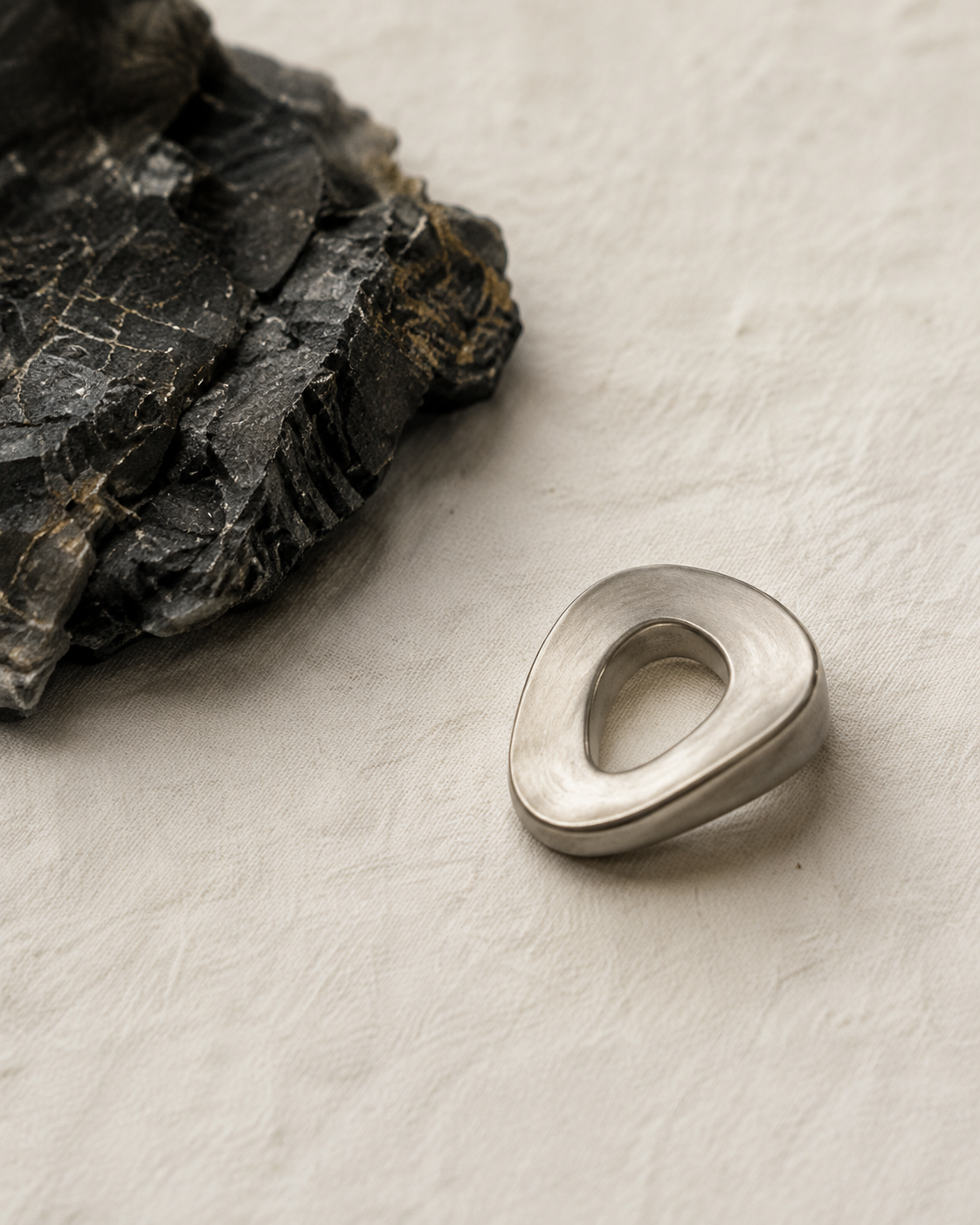 Sculptural metal form beside a dark natural stone